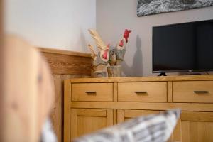 a person sitting in front of a television on a dresser at Torre St Orso 4061 Maison Gerard in Cogne