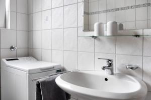 a white bathroom with a sink and a washing machine at Ferienwohnung-Reil in Wardenburg +15 photos