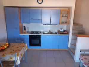 a kitchen with blue cabinets and a table at Casina Torre in Torre Dei Corsari