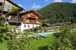 a house with a balcony and chairs in a yard at Feldererhof GsiesApt Dolomitenblick in Valle Di Casies