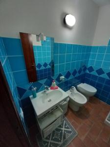 a blue tiled bathroom with a toilet and a sink at Casina Torre in Torre Dei Corsari +21 photos