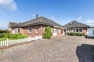 a brick house with a white fence in front of it at Ferienhaus Erlengrund B in Schafstedt