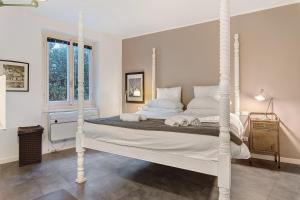 a white bedroom with a white canopy bed at Charming Lake View Bellagio in Bellagio