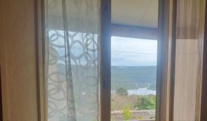 a glass window with a view of a mountain at Oasi Relax Lago Omodeo Casa Demartis in Tadasuni +3 photos