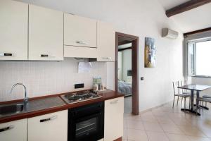 a kitchen with white cabinets and a sink and a table at Bilocale Serra in Bonassola +11 photos