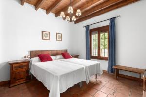 a bedroom with a bed with white sheets and red pillows at Mansión Piedras Blancas in Colmenar