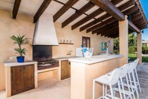 an outdoor kitchen with a stove and chairs at Can Bossa in Capdepera
