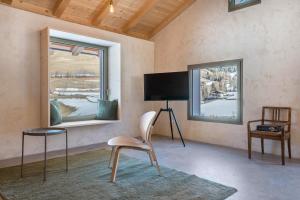 a room with a chair and a tv and two windows at Lena Dolomites Luxury Suite in Villnoss