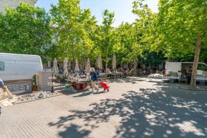 a woman with a stroller walking down a street with a market at En plein centre d'Avignon in Avignon