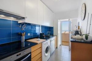 a blue and white kitchen with a washing machine at Moderno e acolhedor com vista mar in Quarteira