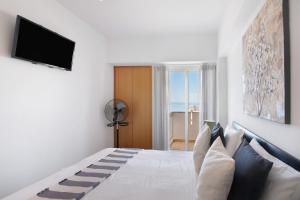a bedroom with a bed with a television and a window at Moderno e acolhedor com vista mar in Quarteira