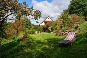 a garden with a bench and a table and a house at La Colline aux Oiseaux in Tieffenbach
