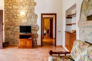 a living room with a stone wall and a tv at Capracotta - Luna in Montemassi