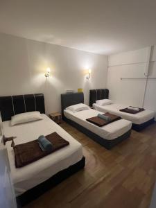 three beds in a room with wooden floors at Comfortable Stay in Ayer Itam