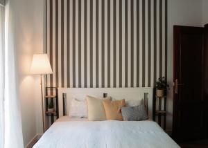 a bedroom with a bed with pillows and a striped wall at Casa de Manuel in Pinos Genil