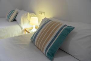 a white bed with a striped pillow and a lamp at Apartamento el Rojo 2 in Can Picafort