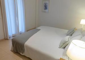 a bedroom with a white bed with two pillows at Apartamento el Rojo 2 in Can Picafort