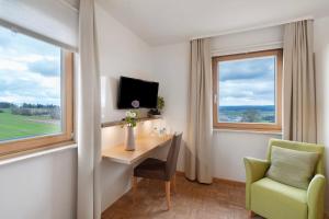 a room with a desk and a chair and windows at Pension Waldliesel in Dornstetten
