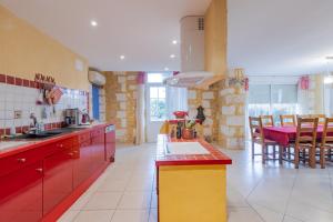 a kitchen with red and yellow cabinets and a table at Maison Sébastien in Saint-Pierre-de-Côle