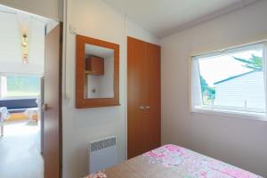 a bedroom with a bed and a mirror and a window at Mobil home 1 Loft in Plouha