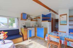a kitchen and dining room with a blue couch and a table at Mobil home 1 Loft in Plouha