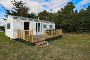a white tiny house with a wooden deck at Mobil home 1 Loft in Plouha +13 photos