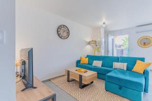 a blue couch in a living room with a clock on the wall at La p'tite maison de Charlotte in Cissac-Médoc