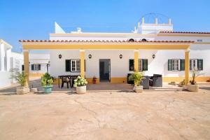 a white house with a patio with a table at Quinta Alegre Tavira Moderno T2 in Luz de Tavira