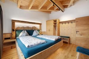 a bedroom with a bed with blue sheets and wooden walls at Oberplatzer in Lagundo
