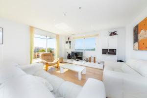 a white living room with a white couch and a table at Ático Las Palmeras in Cala Millor