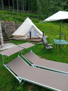 a tent and picnic tables and a table and a chair at Glamping C Selva Tenda Ciliegio in Piano Porlezza