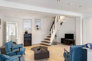 a living room with blue chairs and a staircase at Haus am Nicolaiplatz in Salzwedel