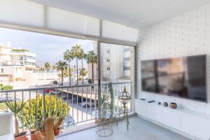 a living room with a large tv and a balcony at Albir Playa in Alfaz del Pi