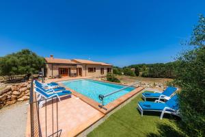 a swimming pool with blue chairs and a house at Finca Ca'n Terrasa in Capdepera