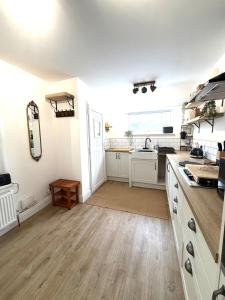 a kitchen with white cabinets and a wooden floor at Joshua House in Newquay