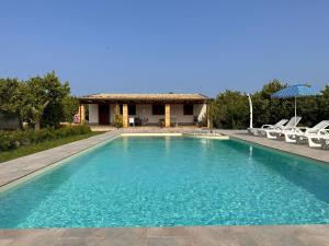 a swimming pool with chairs and a house at Villa Lorenzo in Avola