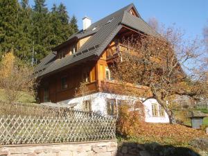a large wooden house with a fence in front of it at Am Neuhausbauernhof in Königsfeld im Schwarzwald +5 photos