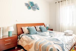 a bedroom with a bed with a flower clock on the wall at Lagoa Residence in Esposende