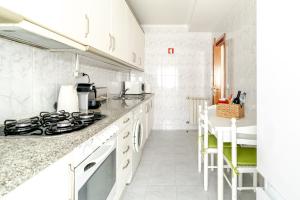 a white kitchen with a stove and a counter at Lagoa Residence in Esposende +8 photos