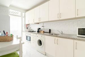 a kitchen with white cabinets and a washer and dryer at Lagoa Residence in Esposende