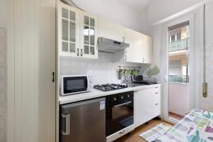 a white kitchen with a stove and a microwave at Marina in Finale Ligure