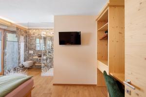 a room with a tv on a wall with a bedroom at Alpi Flo Chalet in Livigno