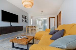 a living room with a yellow couch and a tv at El Pico in La Santa