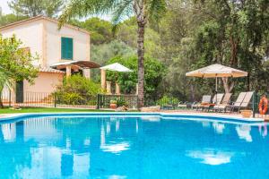 a swimming pool with two umbrellas and a house at Yuma in Llucmajor