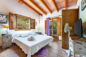 a bedroom with a white bed and a television at Yuma in Llucmajor