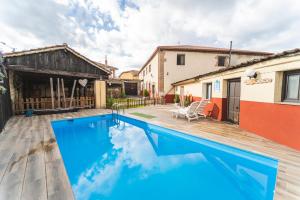 a pool with a wooden deck and a house at Laguna Herrera in Campo de Cuéllar