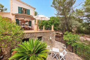 a house with a patio with an umbrella and chairs at Yuma in Llucmajor