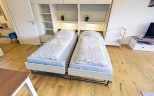 two beds in a room with wooden floors at Höri-Nest Wohlfühl-Appartement in Gaienhofen