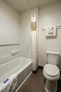 a white bathroom with a toilet and a bath tub at Motel 6-Canoga Park, CA in Canoga Park