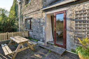 a stone cottage with a red door and a wooden picnic table at finest Retreats - Trimstone Manor, Lee Studio Apartment in Woolacombe